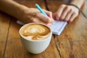Write Ideas - Pesron with Notepad Pen and Coffee